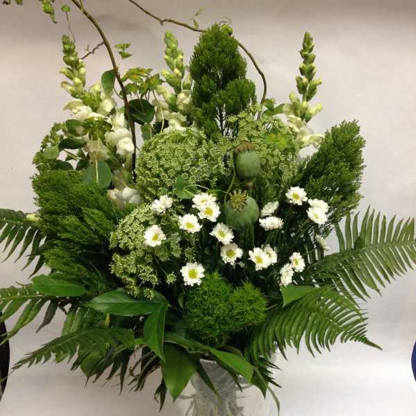 Tall green bouquet with white daisies in a clear glass vase