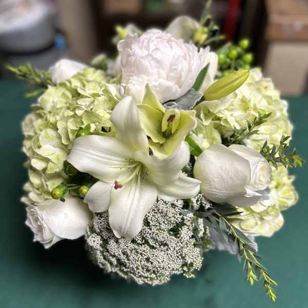 White floral bouquet with lilies, roses, and pale hydrangeas