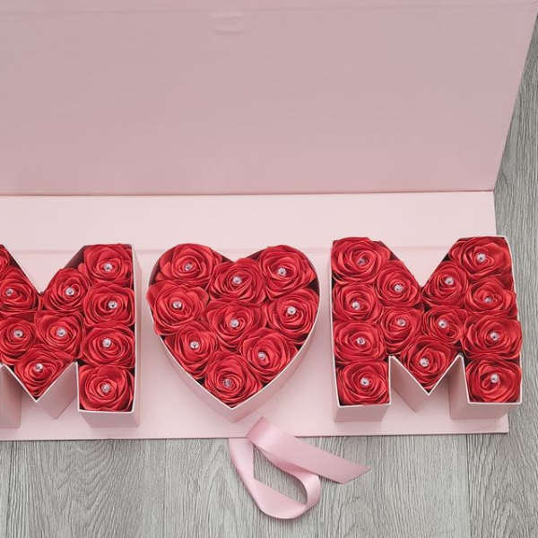 Heart-shaped rose box between two letter boxes with a pink ribbon