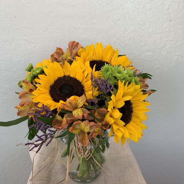 Bouquet of sunflowers and mixed orange flowers in a glass vase