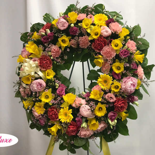 Large circular wreath of pink, yellow, and red flowers on a stand