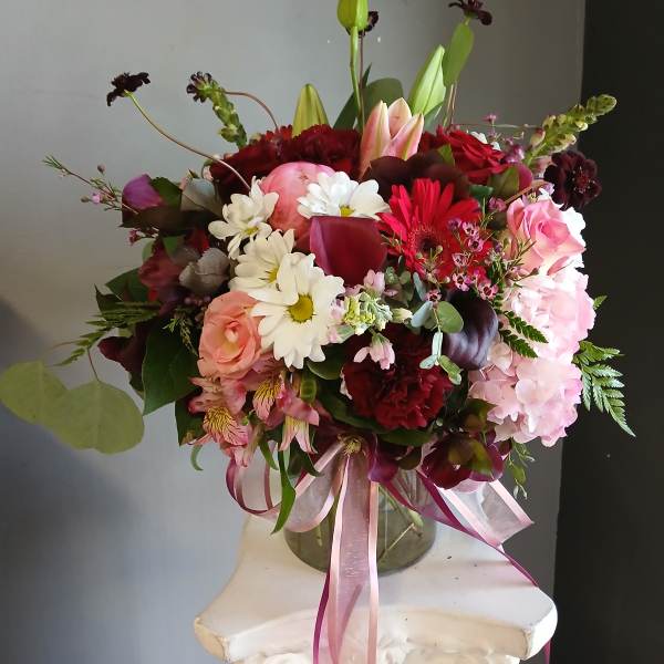 Mixed bouquet with lilies, roses, daisies, and hydrangeas in a glass vase