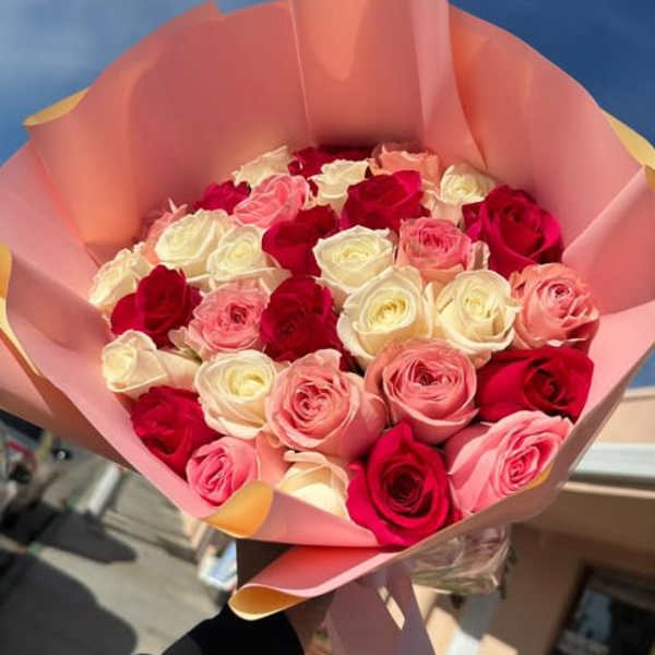 Bouquet of pink, red, and white roses wrapped in pink paper