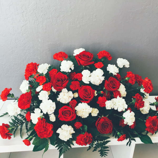 Red roses and red-white carnations arranged low on a white table