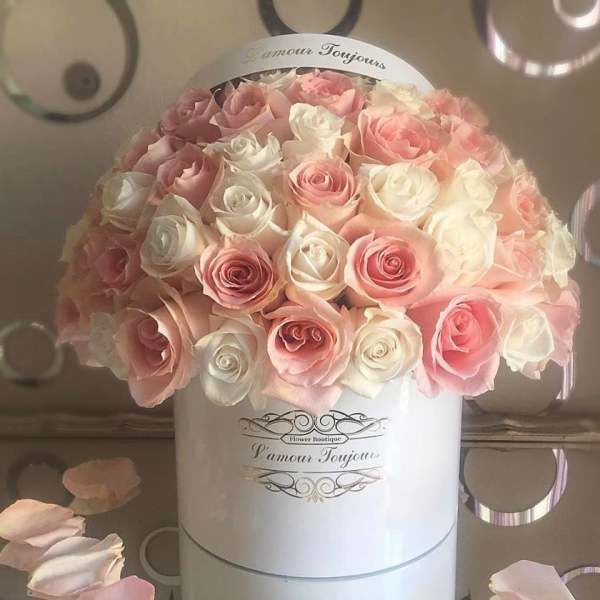 Pink and white roses arranged in a round white hat box