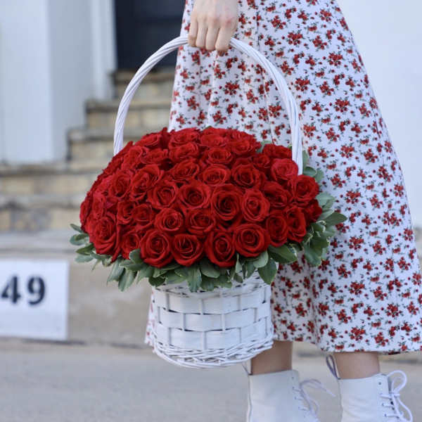 Basket of red roses held by a person in a floral dress