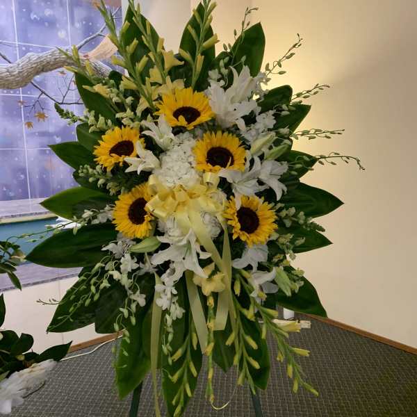 Standing floral spray with sunflowers, white lilies, and yellow blooms