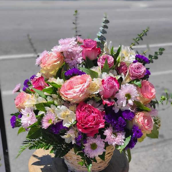 Basket of pink and purple mixed flowers on a stool