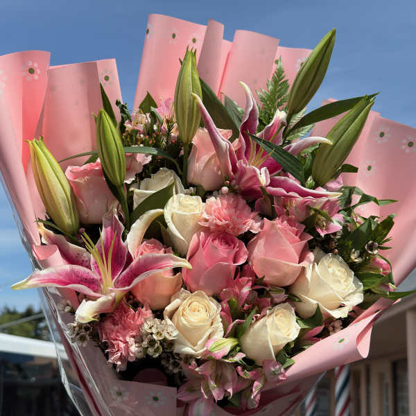 Pink and white bouquet with lilies and roses wrapped in pink paper