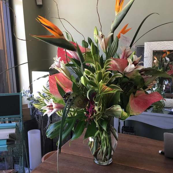 Tall tropical bouquet with lilies and bird-of-paradise in a glass vase