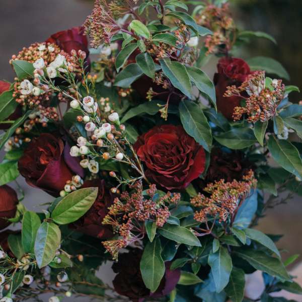 Hand-tied bouquet of deep red roses with white berry sprigs