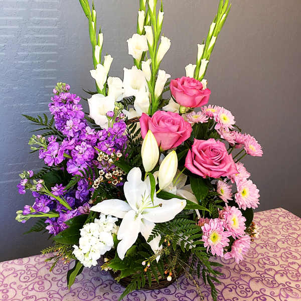 Mixed bouquet with pink roses, white lilies, and purple flowers in a basket