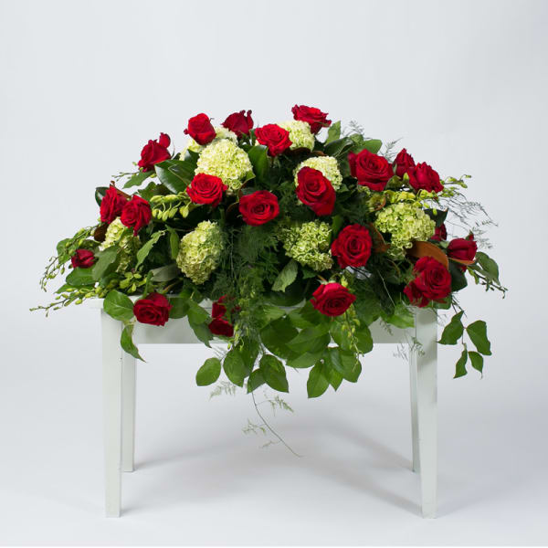 Red roses and pale green hydrangeas arranged on a white table