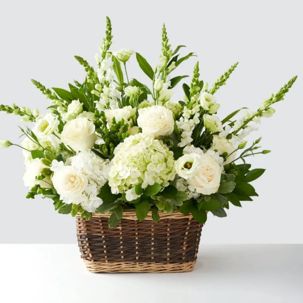 White floral arrangement in a wicker basket with tall green spikes