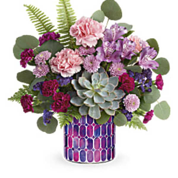 Mixed pink and purple flowers in a patterned vase with a succulent centerpiece