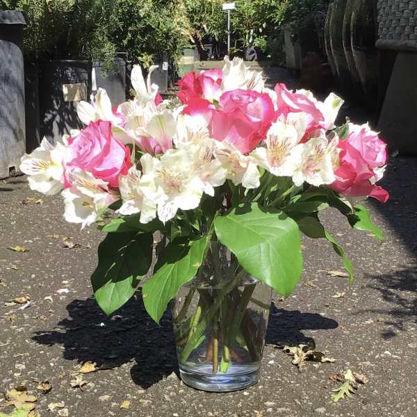 Pink roses and white alstroemeria in a clear glass vase