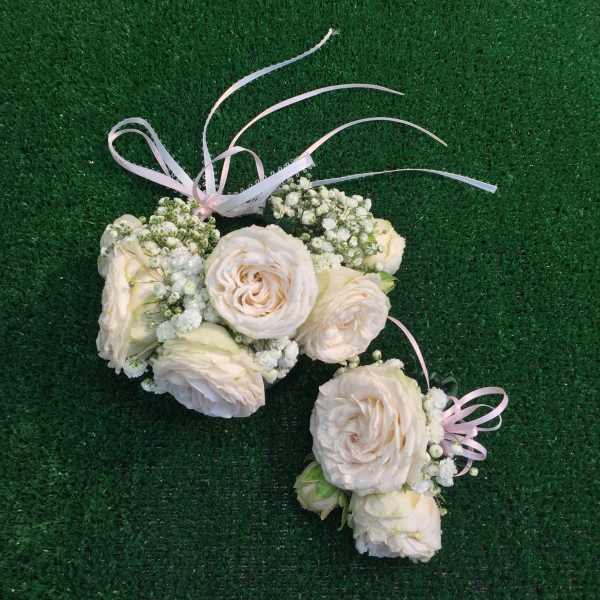 Cream rose floral wrist corsage with pink ribbon on green grass