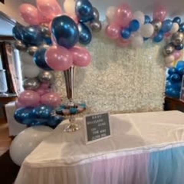 Pink, blue, and silver balloon decorations around a draped table