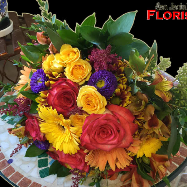 Mixed bouquet of roses, daisies, and other flowers in bright colors