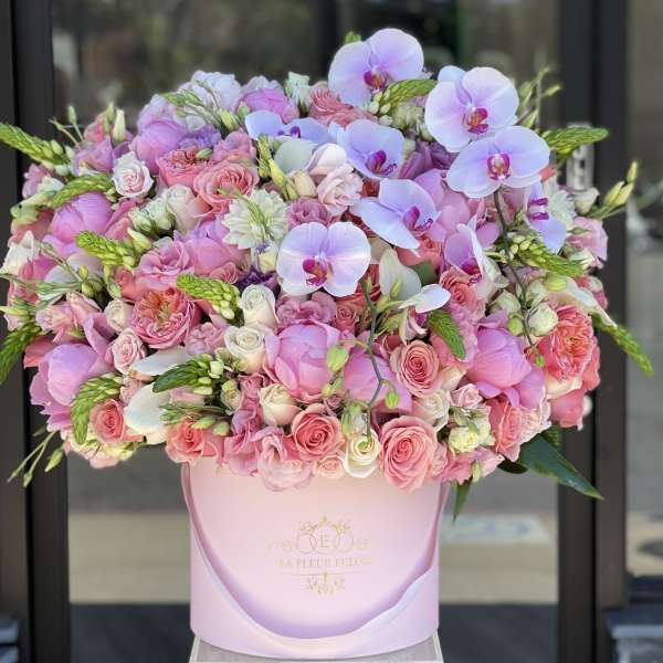 Pink and lavender bouquet with roses and orchids in a pink hatbox