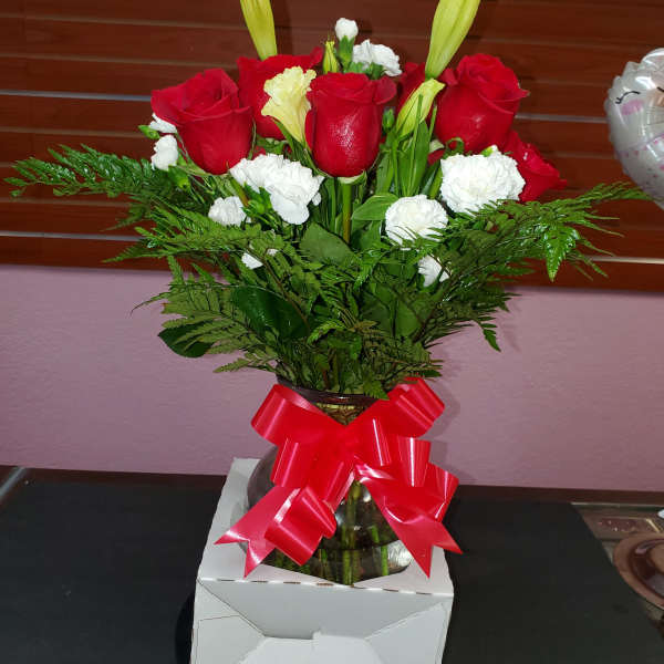 Red roses and white carnations in a glass vase with a red ribbon