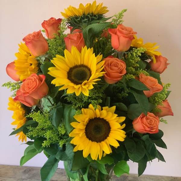 Sunflower and peach rose bouquet in a clear glass vase