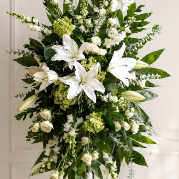 Tall white floral standing spray with lilies and roses on an easel