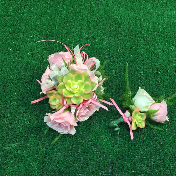 Pink floral corsage and boutonniere with succulents on green turf