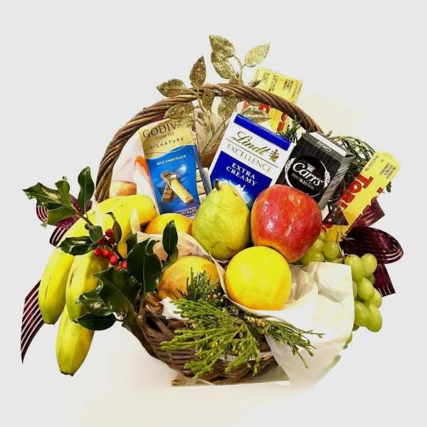 Fruit basket with chocolates and ribbon on a white background
