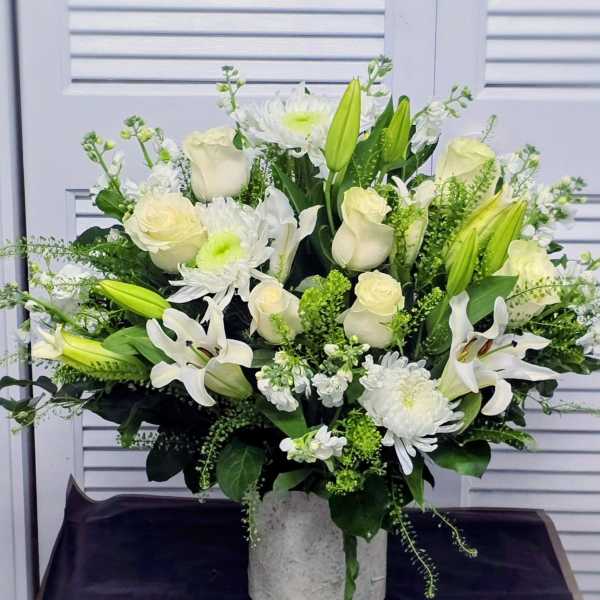 White roses and lilies arranged in a gray vase