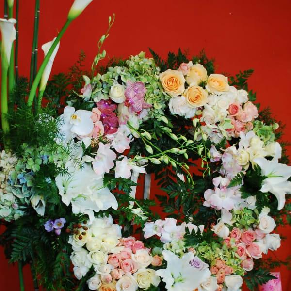 Large floral wreath with roses, orchids, lilies, and calla lilies on an easel