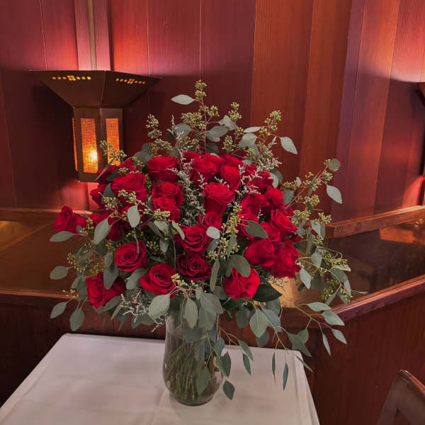 Red rose arrangement in a clear glass vase on a table