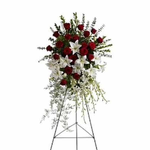 Standing floral spray with red roses and white lilies on a metal easel