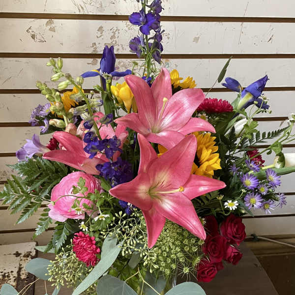 Mixed bouquet with pink lilies, roses, and purple flowers in a glass vase