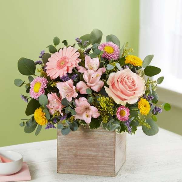 Pink and yellow mixed flower arrangement in a wooden box