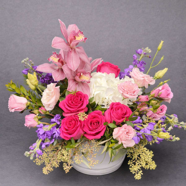 Pink and purple floral arrangement in a white bowl