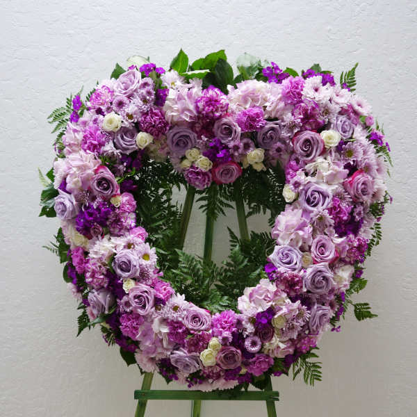 Heart-shaped floral wreath of pink and lavender flowers on a stand