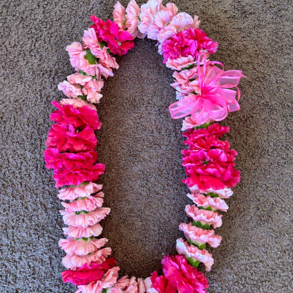 Pink and hot pink carnation lei on a carpeted floor