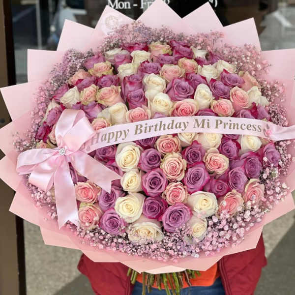 Large bouquet of pink, lavender, and white roses with a pink ribbon
