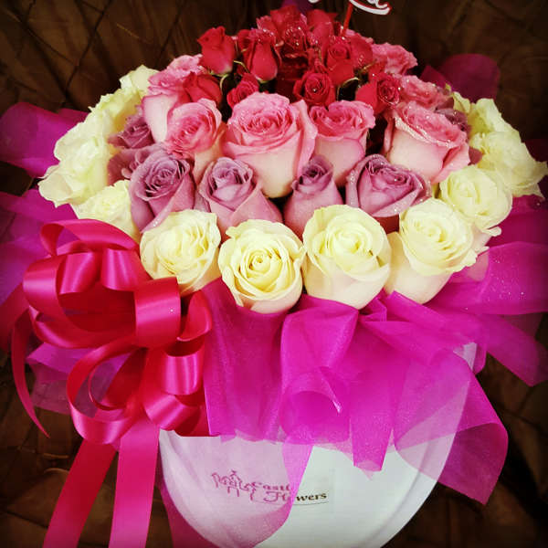 Bouquet of pink, red, and cream roses with a pink ribbon in a white box