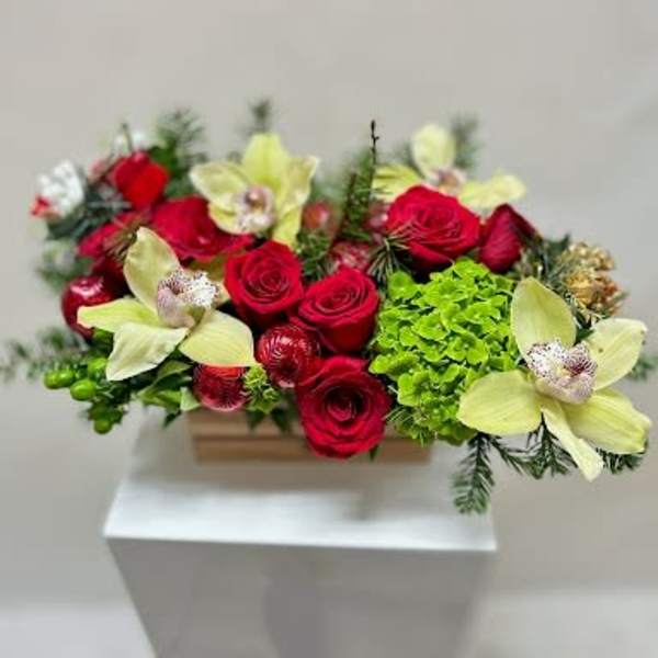 Red roses and pale yellow orchids in a low rectangular container