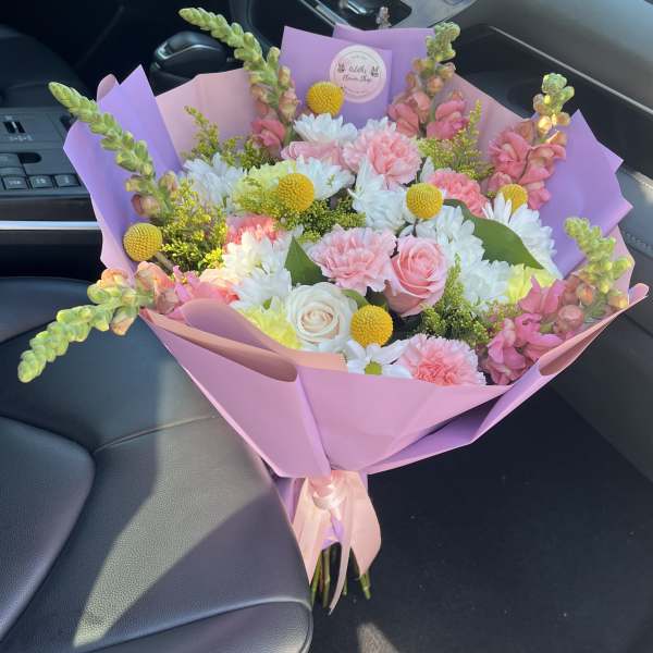Pink and white mixed bouquet wrapped in lavender paper with a satin ribbon