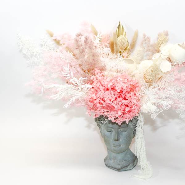 Pink and white dried floral arrangement in a sculpted face vase