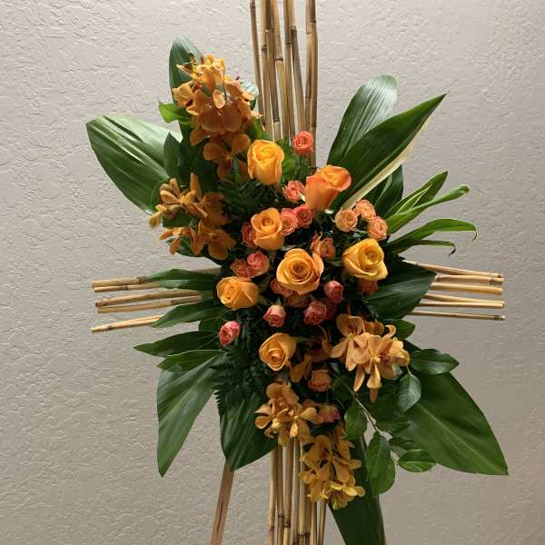 Orange roses and orchids arranged on a bamboo easel cross
