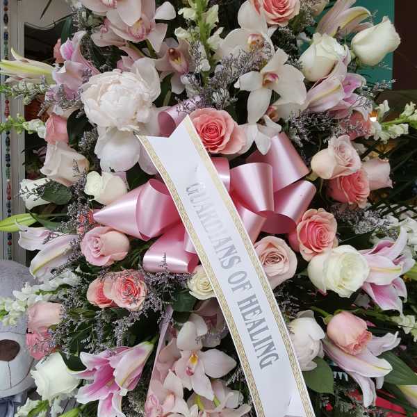 Large pink and white sympathy wreath with a ribbon sash