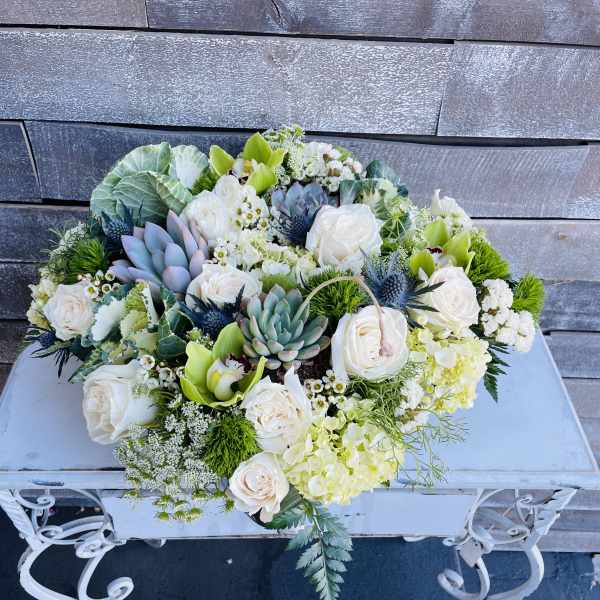 Low floral arrangement with white roses, succulents, and green orchids