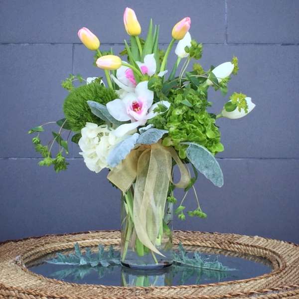 Bouquet of pink-and-yellow tulips with white orchids in a glass vase