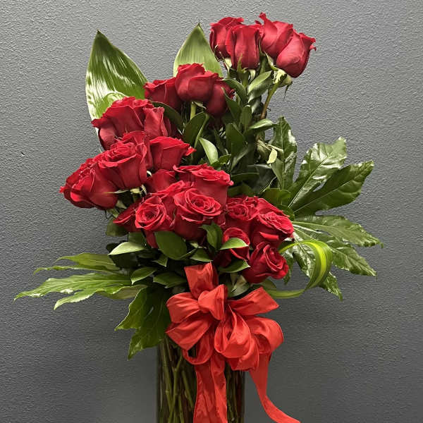 Red roses in a clear glass vase with a red ribbon
