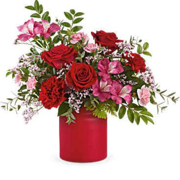 Arrangement of red roses, red carnations, and pink flowers in a matte red cylinder vase