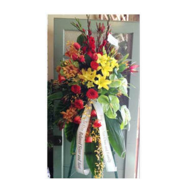 Tall standing floral spray with red, yellow, and orange flowers on an easel